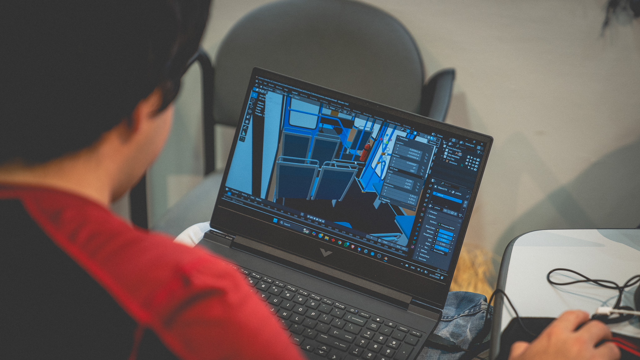 Participante del EXPYLAB modela en Blender el interior de un colectivo durante una sesión del laboratorio — vista sobre el hombro hacia la pantalla con la escena 3D en composición
