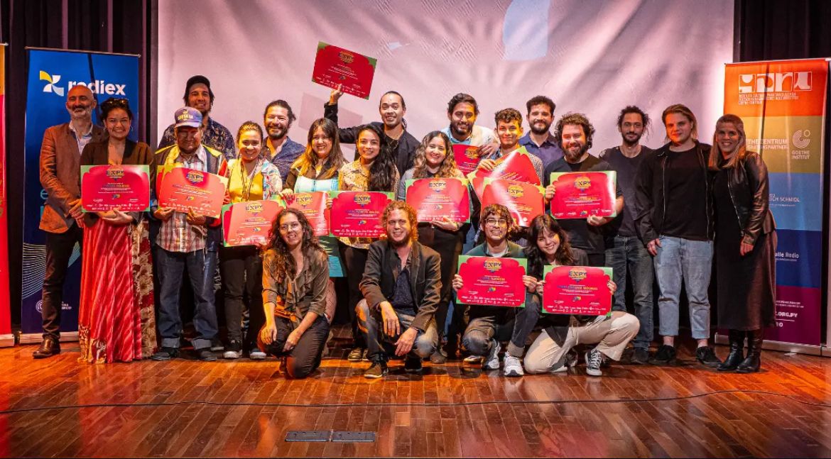 Cierre EXPYLAB — grupo de participantes y aliados posa sobre escenario con certificados rojos del programa, banners institucionales (Ibermedia, ICPA, Goethe) al fondo